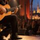 Akustični gitarist na intimnoj koncertnoj pozornici.